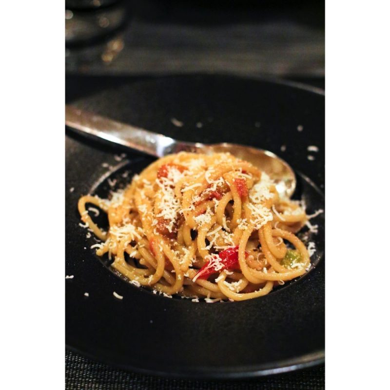 Assiette de pâtes italiennes spaghettoni avec colatura di alici typique d'italie, ail et tomates